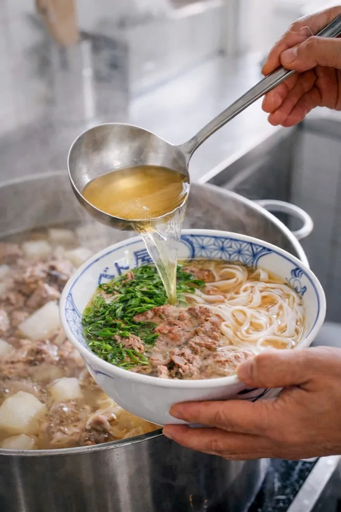 Đầu bếp Viet Origin chan nước dùng nóng từ vá vào bát phở